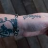 an image of a stainless steel bracelet on the wrist of someone with a wrist tattoo. the bracelet contains segments made from pieces of vintage stainless steel cutlery.
