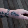 an image of a stainless steel bracelet on the wrist of someone with a wrist tattoo. the bracelet contains segments made from pieces of vintage stainless steel cutlery.