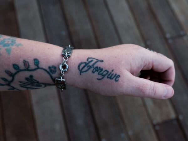 an image of a stainless steel bracelet on the wrist of someone with a wrist tattoo. the bracelet contains segments made from pieces of vintage stainless steel cutlery.