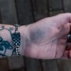 an image of a stainless steel bracelet on the wrist of someone with a wrist tattoo. the bracelet contains segments made from pieces of vintage stainless steel cutlery.