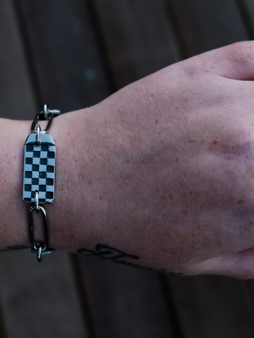 an image of a stainless steel bracelet on the wrist of someone with a wrist tattoo. the bracelet contains segments made from pieces of vintage stainless steel cutlery.