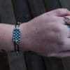 an image of a stainless steel bracelet on the wrist of someone with a wrist tattoo. the bracelet contains segments made from pieces of vintage stainless steel cutlery.