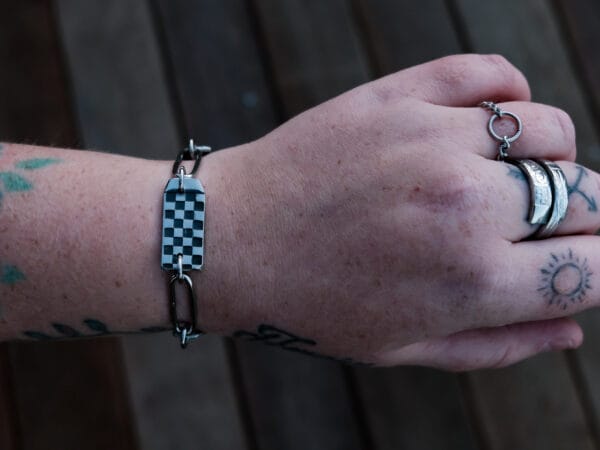 an image of a stainless steel bracelet on the wrist of someone with a wrist tattoo. the bracelet contains segments made from pieces of vintage stainless steel cutlery.