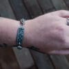 an image of a stainless steel bracelet on the wrist of someone with a wrist tattoo. the bracelet contains segments made from pieces of vintage stainless steel cutlery.