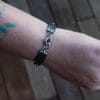 an image of a stainless steel bracelet on the wrist of someone with a wrist tattoo. the bracelet contains segments made from pieces of vintage stainless steel cutlery.