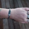 an image of a stainless steel bracelet on the wrist of someone with a wrist tattoo. the bracelet contains segments made from pieces of vintage stainless steel cutlery.