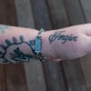an image of a stainless steel bracelet on the wrist of someone with a wrist tattoo. the bracelet contains segments made from pieces of vintage stainless steel cutlery.