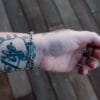 an image of a stainless steel bracelet on the wrist of someone with a wrist tattoo. the bracelet contains segments made from pieces of vintage stainless steel cutlery.