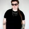 a woman wearing sunglasses, a black shirt and a stainless steel necklace made from the handle and fork tines of a vintage fork.