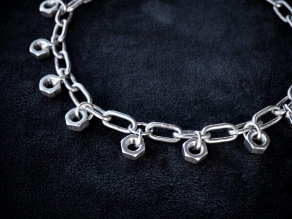 a necklace made from chunky stainless steel chain and hex nuts as charms along it.