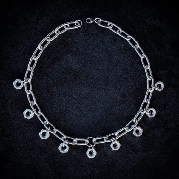 a necklace made from chunky stainless steel chain and hex nuts as charms along it.