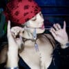 a woman with a red bandana and single top with tattoos wearing a stainless steel pendant made from a thrifted fork placed on a small black cushion for a product photoshoot