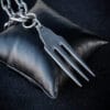 a stainless steel pendant made from a thrifted fork placed on a small black cushion for a product photoshoot
