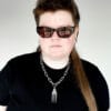 a woman with sunglasses and a black shirt wearing a stainless steel pendant made from a thrifted fork placed on a small black cushion for a product photoshoot