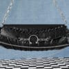 a product photo of a black faux leather handbag with spikes and chains.