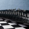 a product photo of a black faux leather handbag with spikes and chains.
