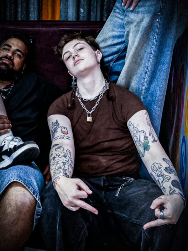 a person with tattoos and a padlock necklace pulling the fingers in a brand photoshoot