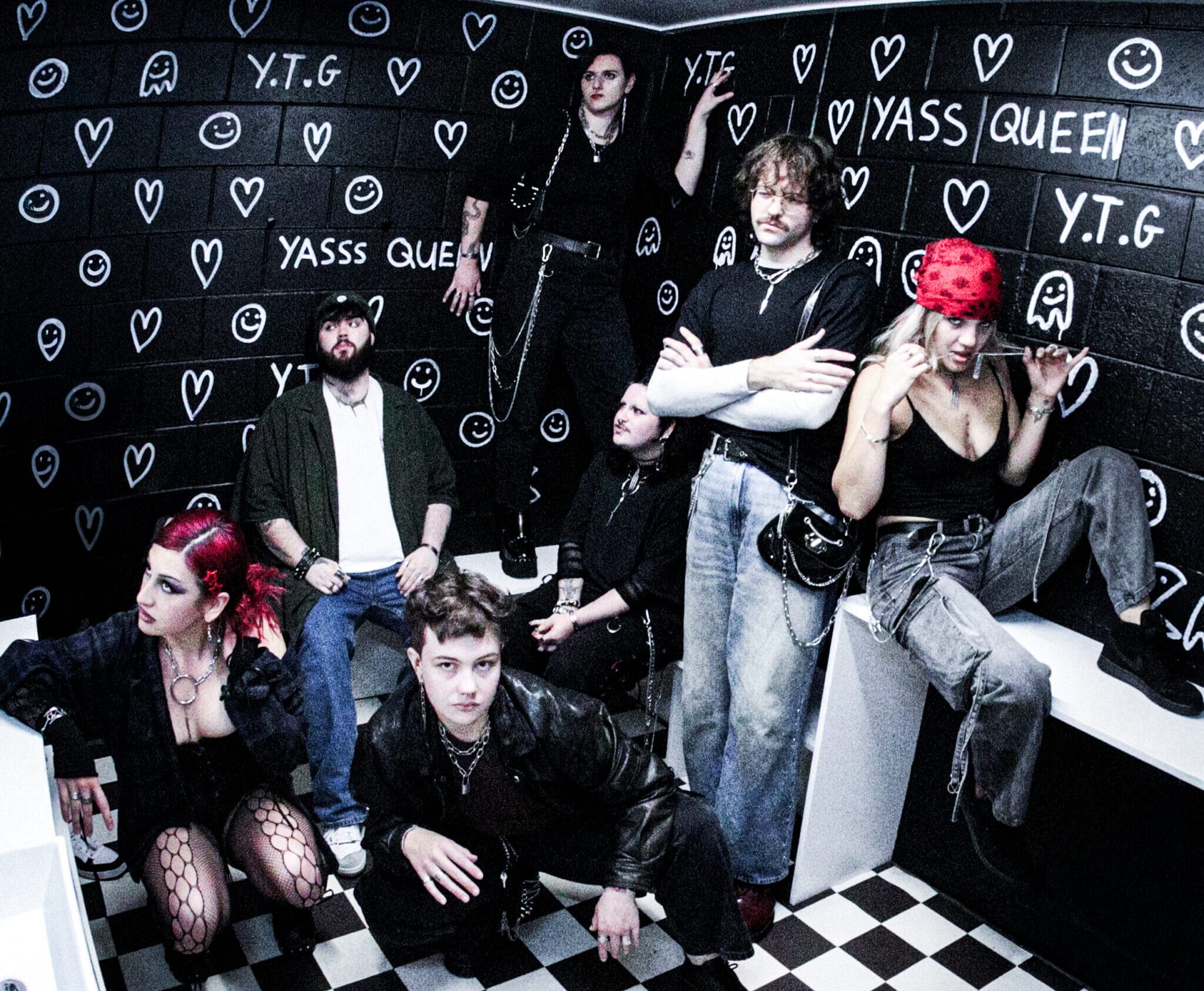 a group of people post in a quirky alternative bathroom with graffiti on the wall for a brand photoshoot.